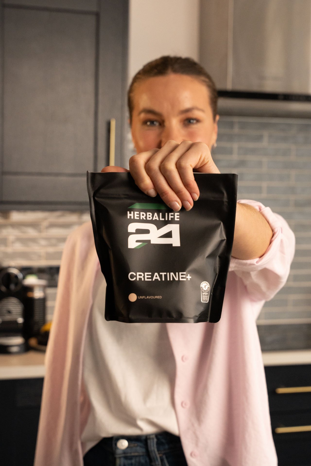 Mujer sosteniendo bolsa de herbalife 24 con creatina
